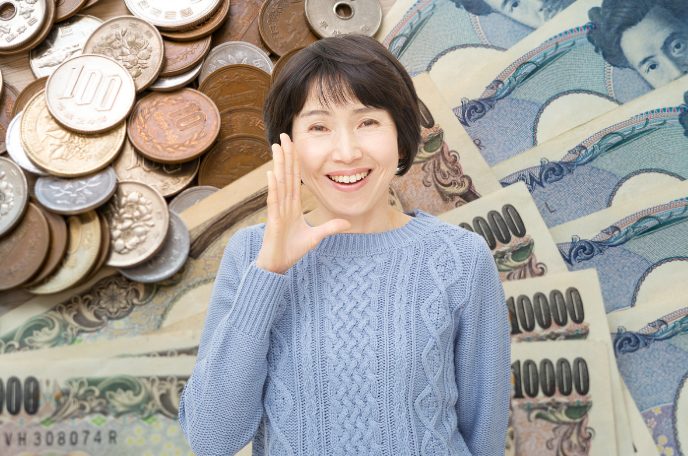 お金の前で右手を口元にくの字に当てて微笑む中年女性のイメージ