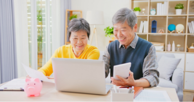 中年夫婦が机のノートパソコンに向かって笑顔で検索している